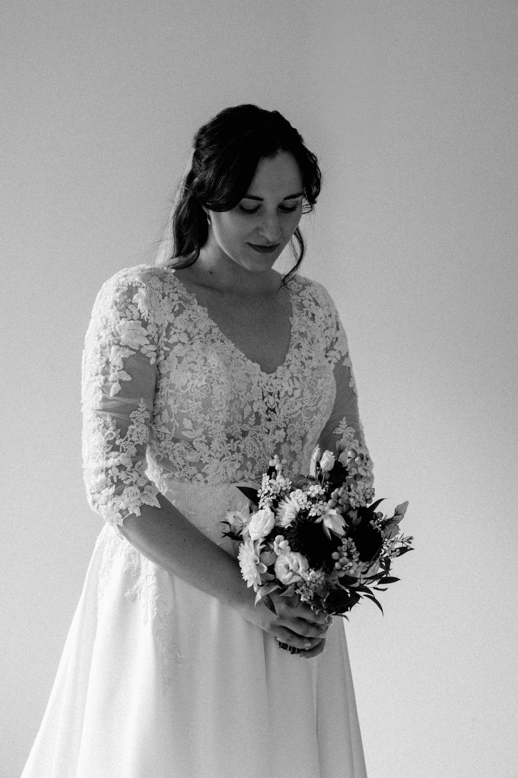 Schwarz weiß Bild von einer Braut die auf ihren Brautstrauß blickt.